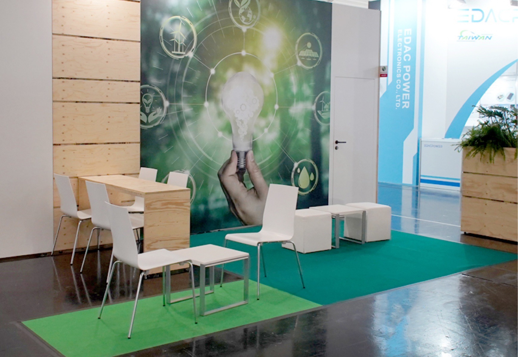 Lounge für electronica 2024 mit Hochtisch, Stühlen und Hockern, Großflächengrafik mit Glühbirne