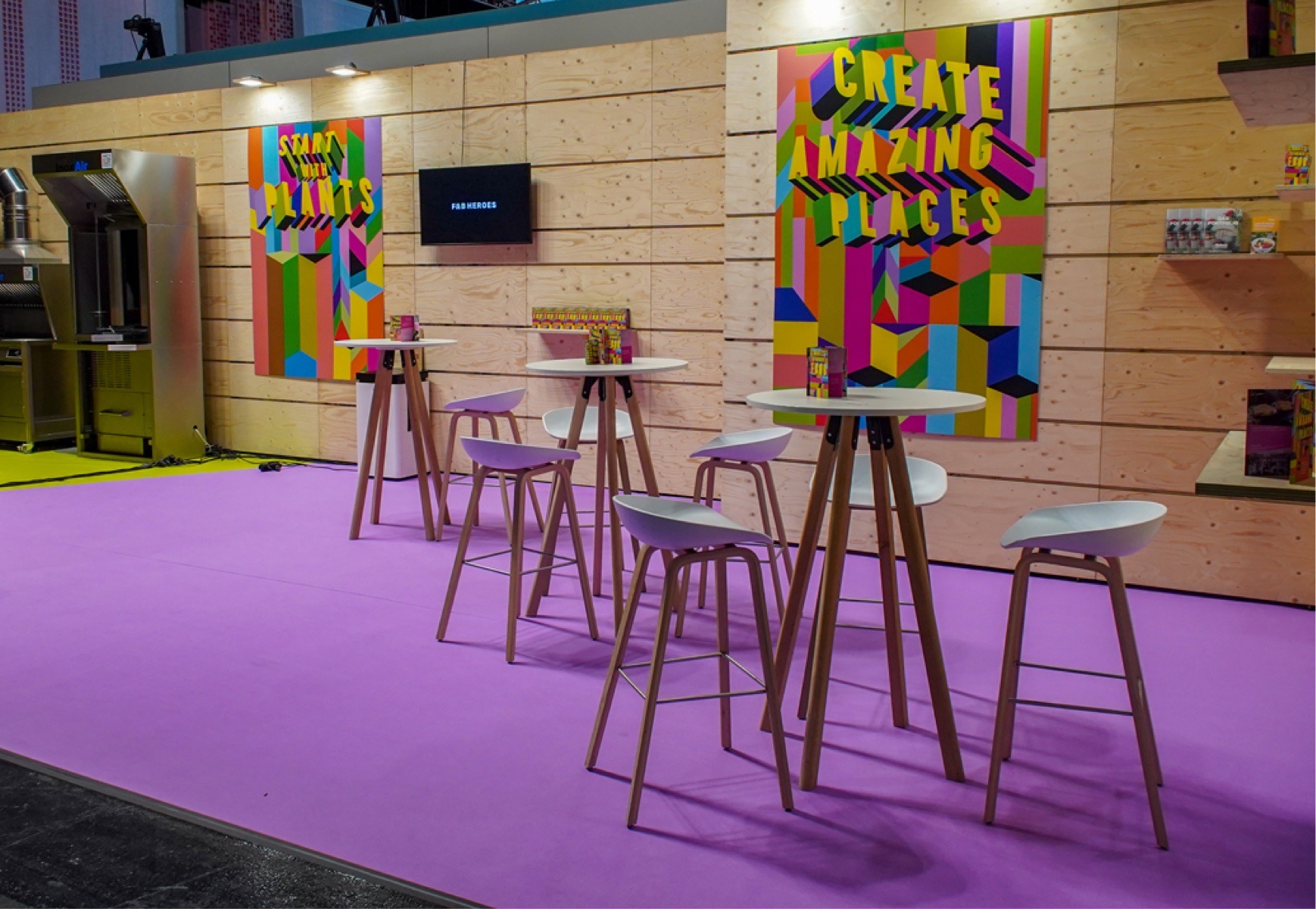 Gastrofläche für die Expo Real 2023, Hochtische und Stühle, Wand mit großen farbintensiven Plakaten
