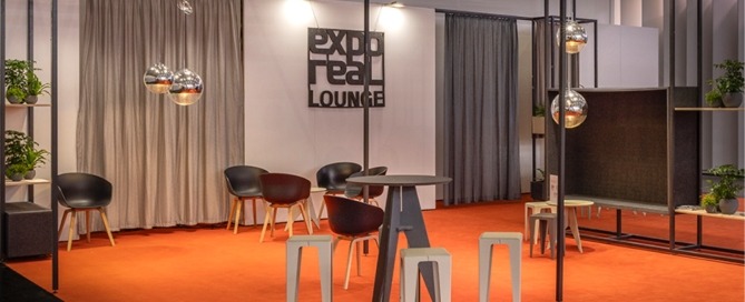 Lounge für die exporeal 2025 mit Hochtischen und Stühlen, Trennelementen