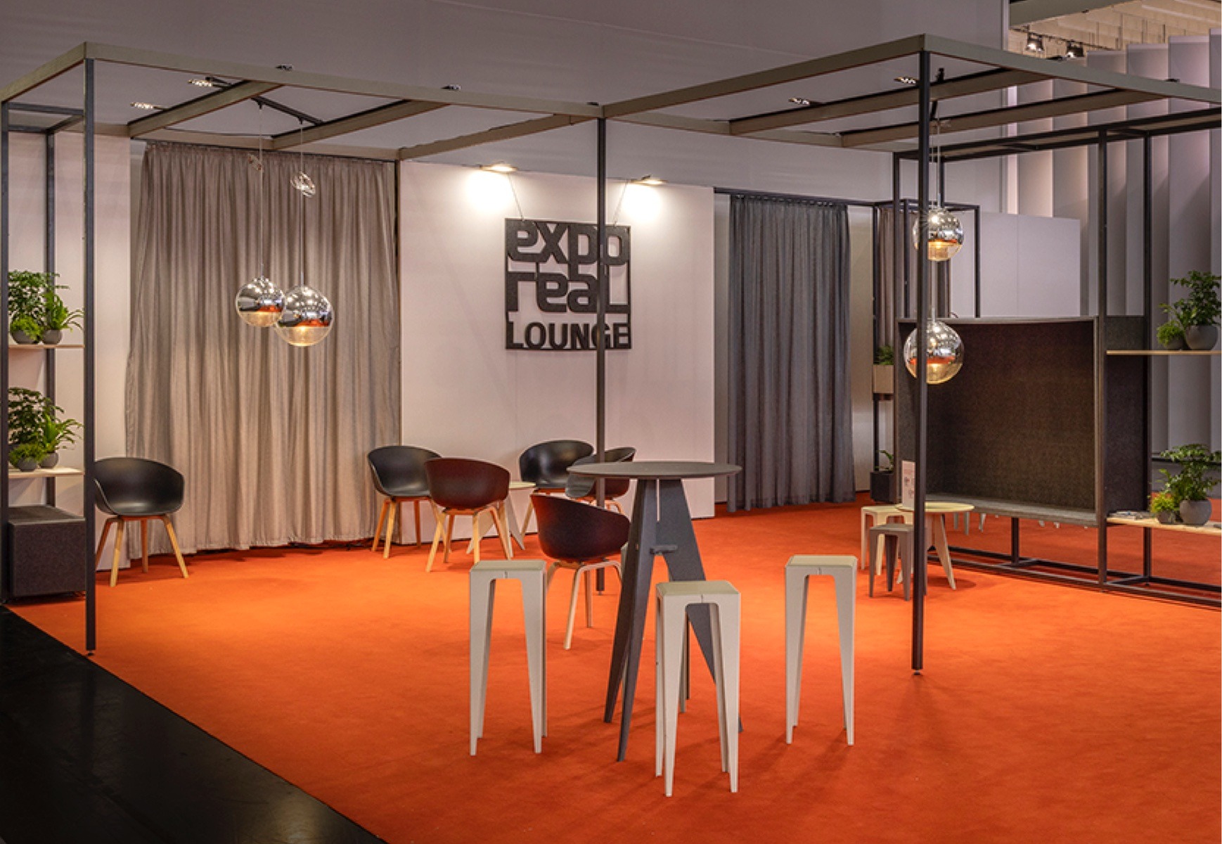 Lounge für die exporeal 2025 mit Hochtischen und Stühlen, Trennelementen