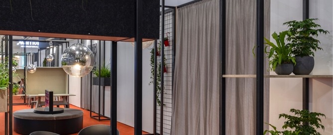 Lounge für die exporeal 2025 mit Hochtischen und Stühlen, Trennelementen und Vorhängen