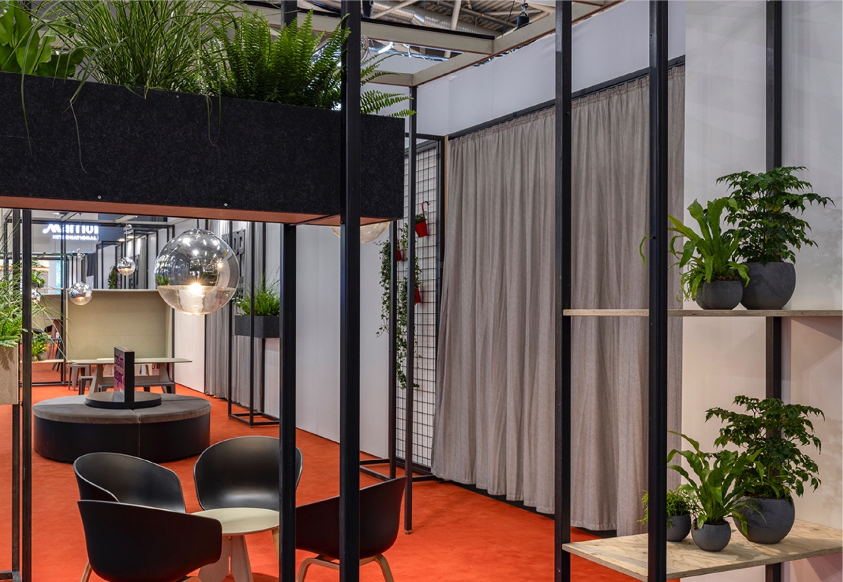 Lounge für die exporeal 2025 mit Hochtischen und Stühlen, Trennelementen und Vorhängen
